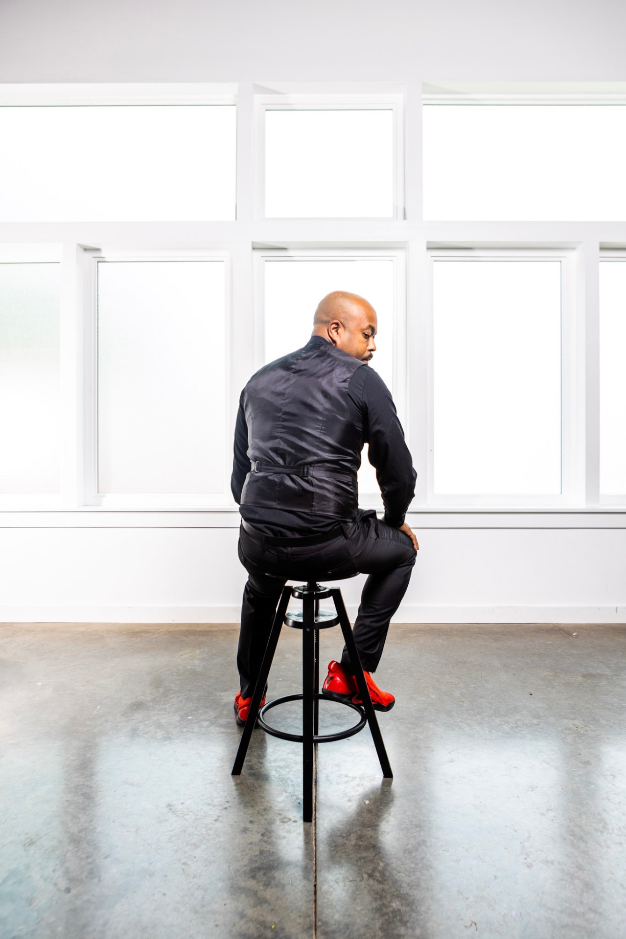 Remy on a stool in a bright studio with red sneakers